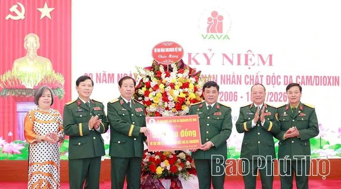 Trung tướng Nguyễn Hữu Chính - Chủ tịch Hội Nạn nhân chất độc da cam/dioxin Việt Nam trao biểu trưng hỗ trợ sinh kế và tặng hoa chúc mừng.
