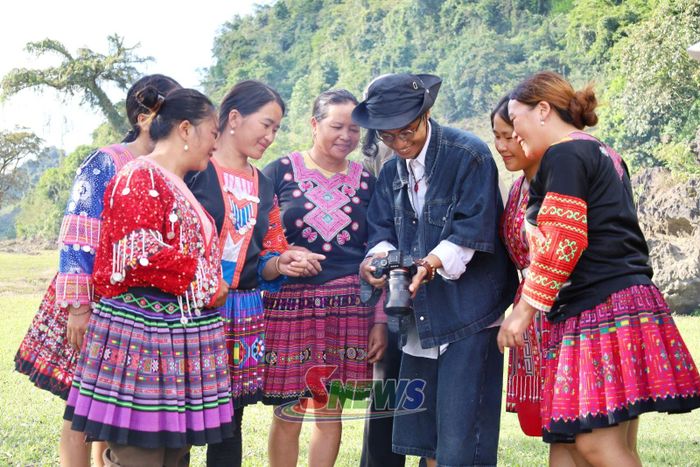 Du khách chụp ảnh cùng người dân bản địa tại điểm du lịch Làng đá dựng tại bản Tà Phềnh.
