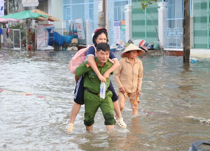Công an phường Bình Thủy giúp người dân qua khu vực ngập nước do triều cường.