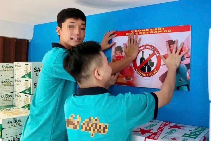Nhân viên cơ sở kinh doanh dán banner tuyên truyền về phòng, chống vi phạm nồng độ cồn