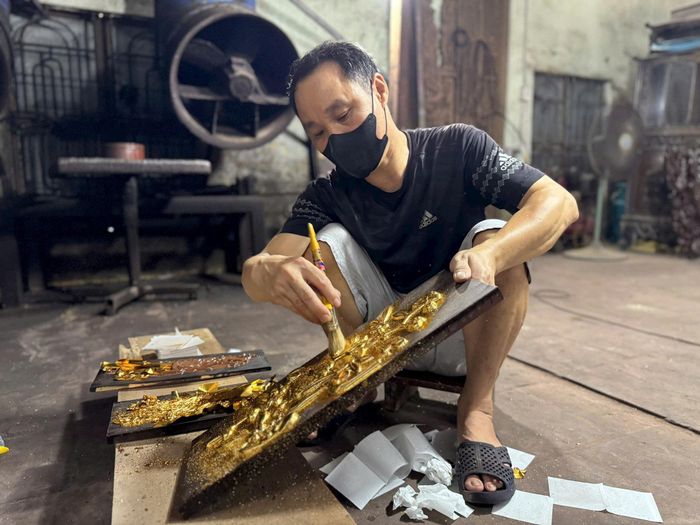 Người thợ đang thếp vàng lên sản phẩm thủ công bằng gỗ. Ảnh: Hoàng Lân
