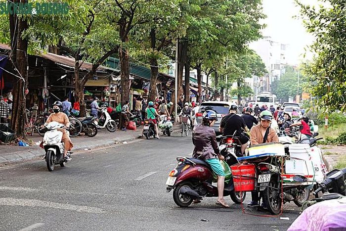 Hoạt động buôn bán diễn ra ngay dưới lòng đường, nhiều người mua, bán dừng đỗ xe khiến không gian lưu thông bị thu hẹp. (Ảnh Linh Vũ)