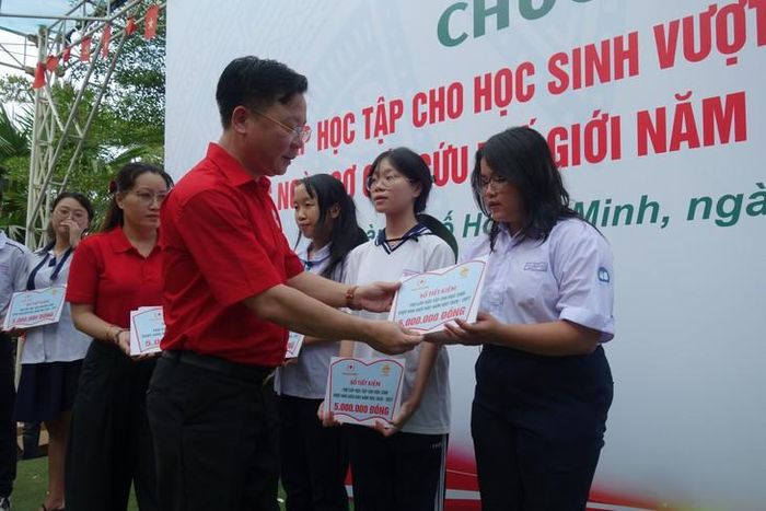 Phó Chủ tịch Trung ương Hội Chữ thập đỏ Việt Nam Nguyễn Sỹ Trường trao tặng sổ tiết kiệm cho các em học sinh có hoàn cảnh khó khăn, vượt khó, hiếu học. Ảnh: QA