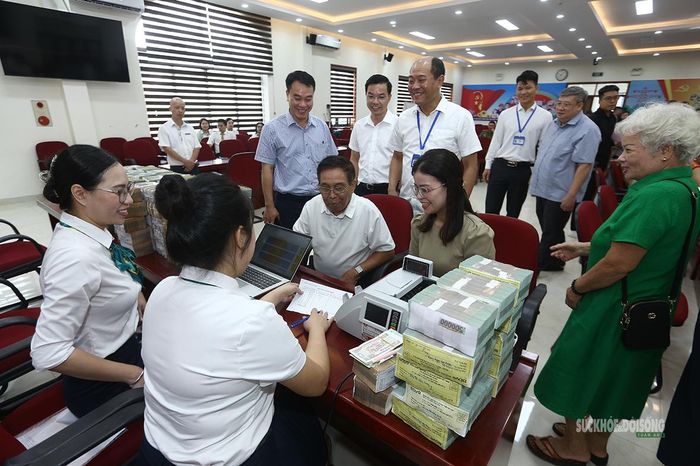 Người dân vui vẻ trao đổi cùng cán bộ, nhân viên ngân hàng trong quá trình nhận tiền bồi thường. Ảnh: Tuấn Anh