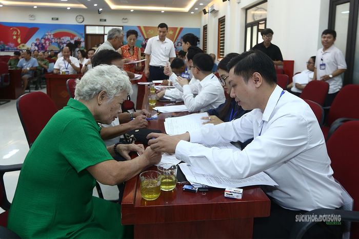 Cán bộ hướng dẫn người cao tuổi kiểm tra giấy tờ, hoàn tất thủ tục nhận tiền. Ảnh: Tuấn Anh