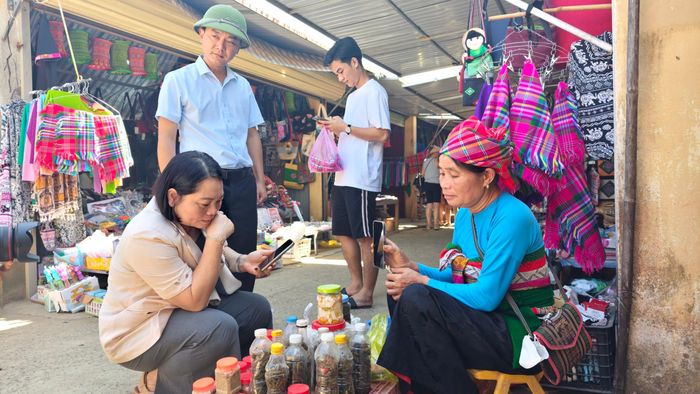 Bà Bùi Thị Hoa - Bí thư Đảng ủy, Chủ tịch HĐND xã Pù Luông (ngồi bên trái) trước sạp hàng nhỏ ở chợ Phố Đoàn. Ảnh: Huy Thông