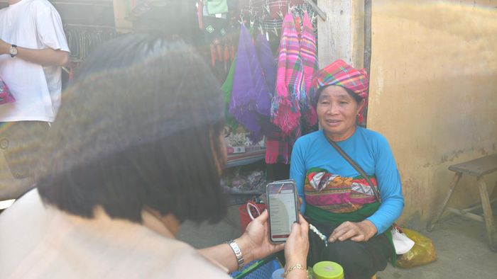 Bà Bùi Thị Hoa quét mã QR thanh toán cho người dân sau khi mua hàng. Ảnh: Huy Thông