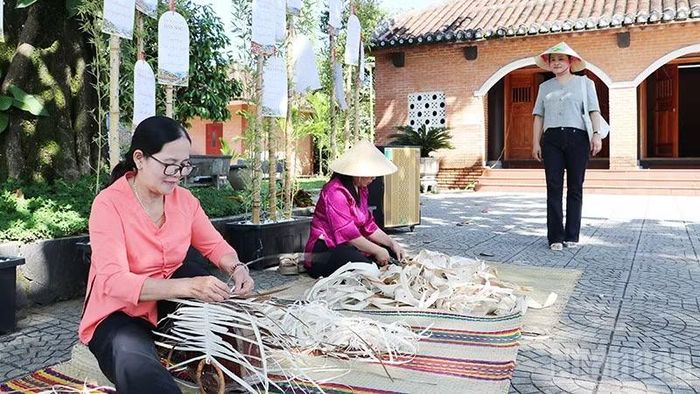 Du khách trải nghiệm tìm hiểu kỹ thuật nghề thủ công làm sản phẩm từ mo cau tại làng cổ Lộc Yên. (Ảnh: ANH QUÂN)