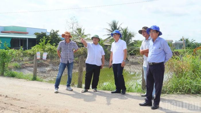 Lãnh đạo Đảng ủy và Ủy ban nhân dân xã Tân Trụ thị sát thực tế để tháo gỡ khó khăn trong việc giải phóng mặt bằng công trình giao thông trọng điểm đi qua địa bàn xã. (Ảnh: THANH PHONG)