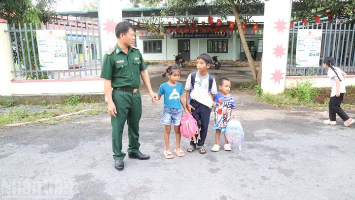 Cán bộ Đồn Biên phòng Sêrêpốk hỗ trợ các cháu trong buôn đi học về. (Ảnh: CÔNG LÝ)