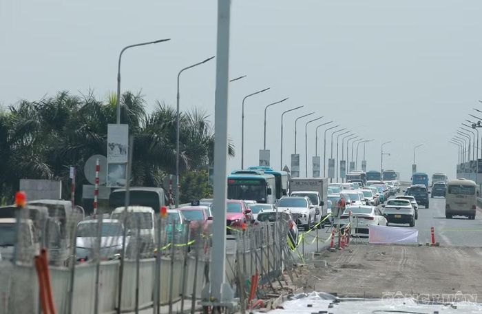 Đến khoảng 12h cùng ngày, lưu lượng phương tiện qua khu vực đã giảm so với buổi sáng. Tuy nhiên, tại vị trí thi công trạm cân tải trọng, mặt bằng bị thu hẹp khiến các phương tiện, đặc biệt là ô tô, phải di chuyển chậm để đi qua khu vực rào chắn.
