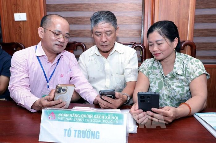 Cán bộ NHCSXH hướng dẫn khách hàng mở tài khoản thanh toán tại điểm giao dịch xã Trung Chính. Ảnh: Trần Việt - TTXVN