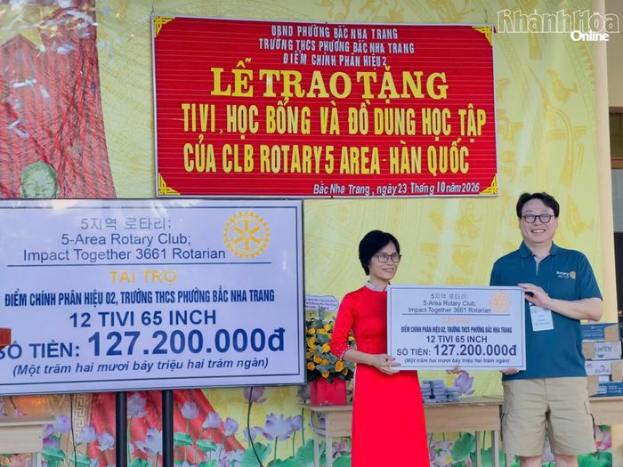 Đại diện đơn vị tài trợ trao bảng tượng trưng tặng 12 ti vi cho lãnh đạo nhà trường.