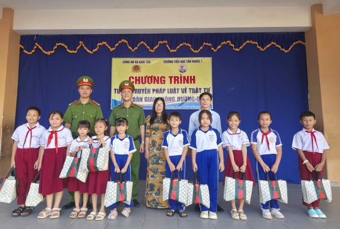 Đại diện Công an xã Hàm Tân và Trường Tiểu học Tân Nghĩa 1 trao tặng mũ bảo hiểm cho học sinh tại chương trình tuyên truyền pháp luật về an toàn giao thông. (Ảnh: CALĐ).