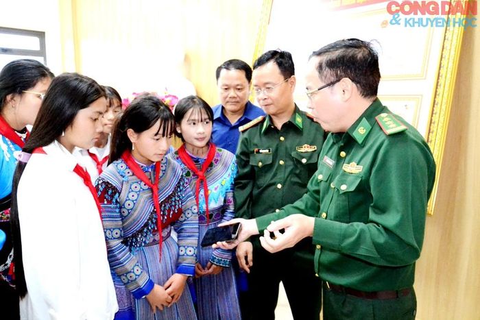 Cán bộ Biên phòng Lào Cai hướng dẫn các em học sinh cách sử dụng điện thoại quét mã QR để tìm hiểu, học tập về đường biên, cột mốc và truyền thống Bộ đội Biên phòng Lào Cai. Ảnh: Quốc Hồng
