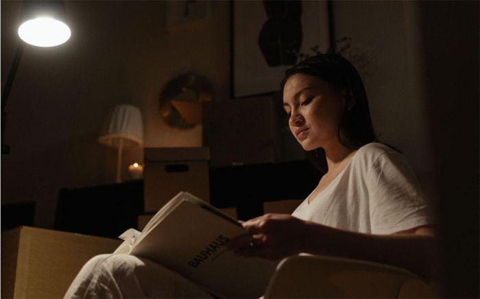 Đọc sách giấy dưới ánh sáng dịu giúp thư giãn trước khi quay lại giường.