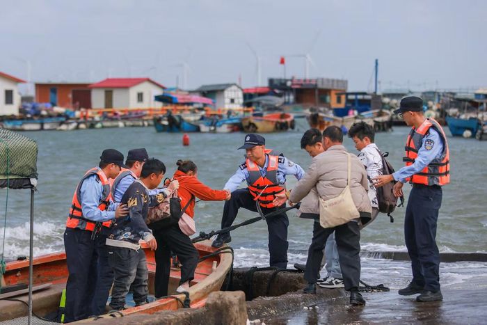 Cảnh sát hỗ trợ người dân lên bờ sơ tán khi bão Champi tiến gần. (Ảnh: Reuters)