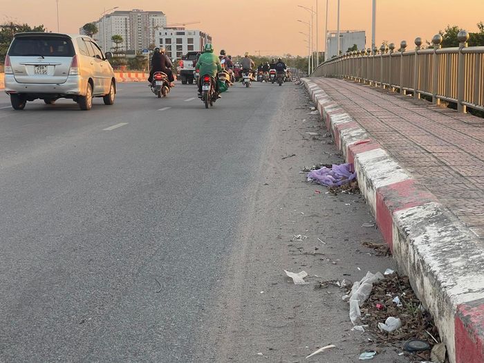 Rác, cát bui dày đặc trên mặt đường cầu vượt đường sắt gây khó khăn cho người tham gia giao thông mỗi khi có gió lớn. Ảnh: PV