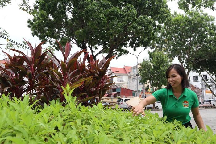 Trưởng thôn Điền Hòa Cát Hoàng Thị Hiên tham gia cắt tỉa cây xanh trong khuôn viên làng. Ảnh: NM