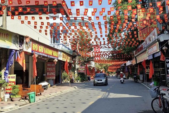 Tuyến đường vào khu vực Lễ hội vinh danh làng nghề ở thôn Vạn Điểm, xã Phú Xuyên được trang trí cờ hoa rực rỡ. Ảnh: PV