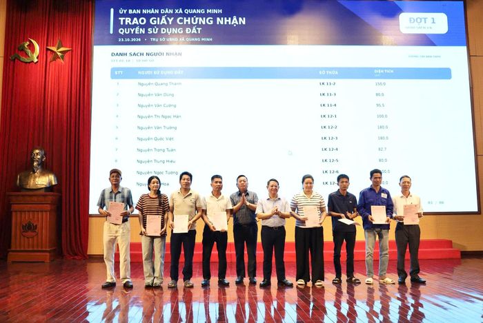 Lãnh đạo xã Quang Minh trao Giấy chứng nhận quyền sử dụng đất cho các hộ gia đình. Ảnh: PV
