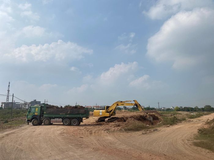 Xe tải trọng lớn không che chắn, lấy đất từ bãi tập kết cạnh quốc lộ 32 để san lấp, làm đường công vụ tại dự án nâng cấp đường liên xã Tam Hiệp - Tam Thuấn, xã Hát Môn (ảnh chụp ngày 21-10). Ảnh: PV