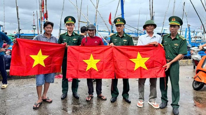 Cán bộ, chiến sĩ Đồn Biên phòng Tuy Hòa trao cờ Tổ quốc tặng ngư dân. (Ảnh: NGUYỄN LÂN)