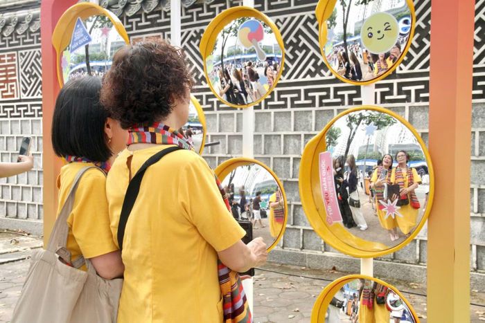 Du khách hào hứng chụp ảnh kỷ niệm tại góc check-in gương cầu lồi được trang trí độc đáo.