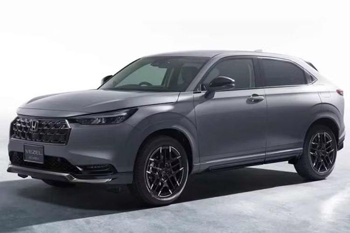 Điểm thay đổi dễ nhận biết trên tất cả các phiên bản Honda Vezel 2027 là phần chóa đèn chiếu sáng phía trước được làm tối màu, mang lại vẻ ngoài cá tính hơn. Ở các biến thể cao cấp như e:HEV Z và gói Play Package, toàn bộ phần ốp nhựa bảo vệ quanh hốc bánh và cản xe trước/sau chuyển sang sơn cùng màu thân xe thay vì để nhựa đen nguyên bản.