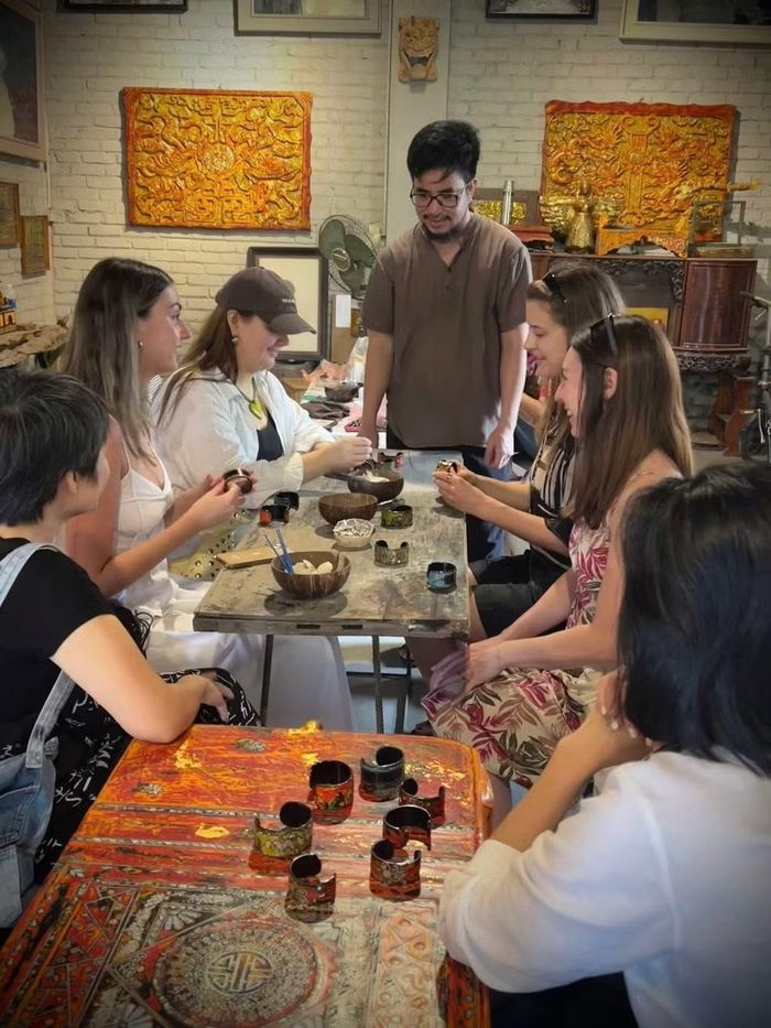 Nghệ nhân Nguyễn Tấn Phát hướng dẫn du khách trải nghiệm làm sản phẩm sơn mài. Ảnh: FBNV