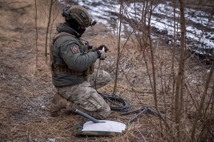 Một binh sĩ Ukraine cài đặt điểm kết nối Starlink. (Ảnh: Reuters)