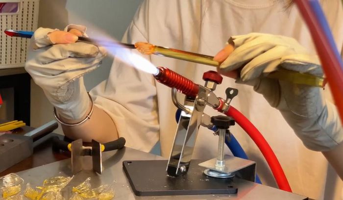 Cô gái nung các ống thủy tinh để tạo hình cánh hoa theo mong muốn