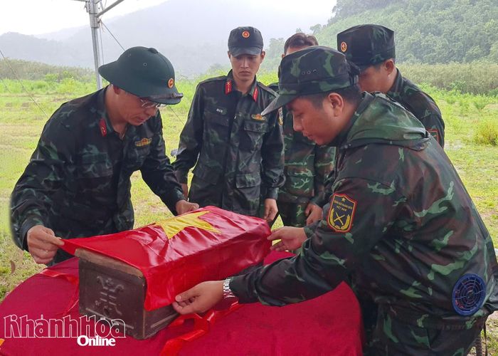 Cán bộ, chiến sĩ trang trọng phủ Quốc kỳ bên ngoài quách hài cốt liệt sĩ trước khi di chuyển về nghĩa trang liệt sĩ, chuẩn bị tổ chức lễ viếng, truy điệu và an táng.