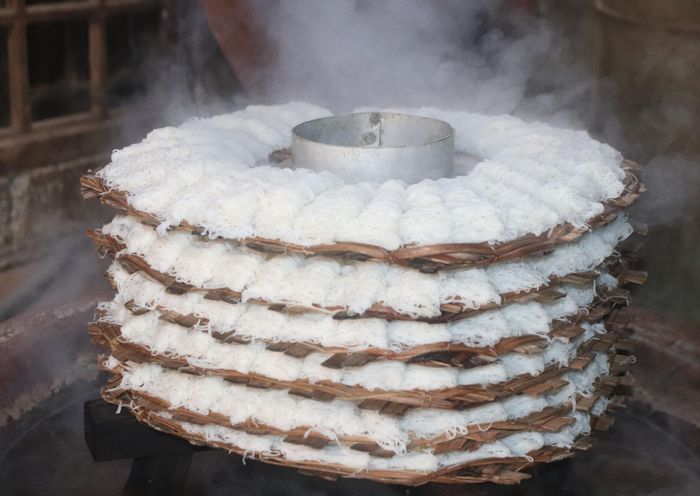 Những sợi bánh được người thợ khéo léo trải lên các khay tròn bằng tre rồi hấp chín