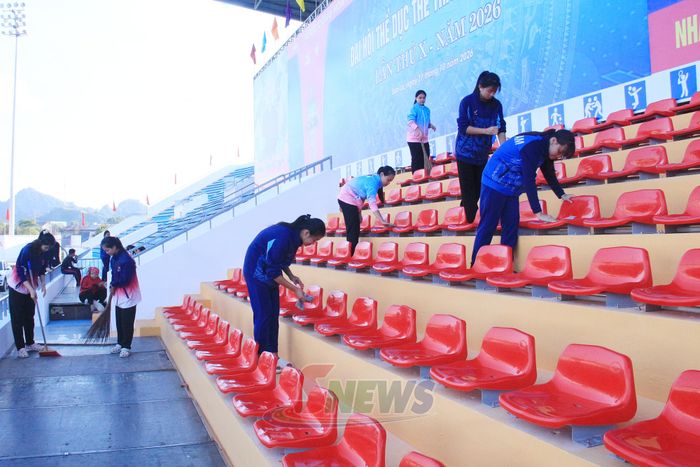 Các em học sinh tham gia dọn dẹp khán đài tại sân vận động.