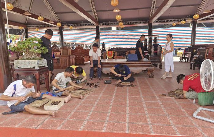 Nội dung thi biểu diễn tay nghề đục gỗ, các nghệ nhân, thợ giỏi ở làng nghề mộc cao cấp Vạn Điểm tập trung tạo ra sản phẩm bức tranh hoa hồng bằng chất liệu gỗ. Ảnh: PV