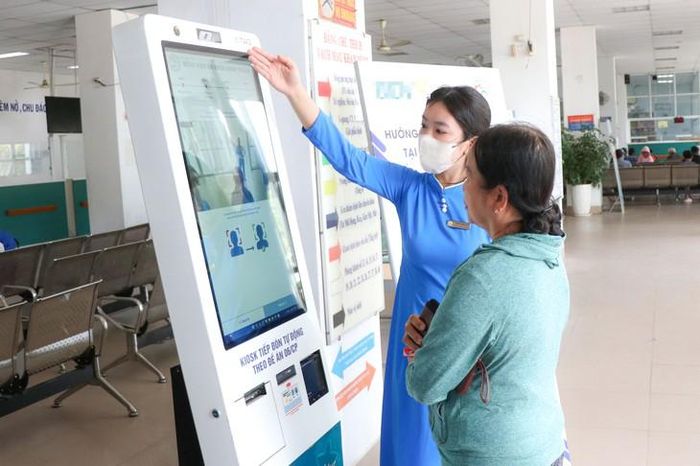 Nhân viên Bệnh viện Đa khoa Ninh Thuận hướng dẫn người dân đăng ký dịch vụ khám, chữa bệnh qua hệ thống điện tử Kiosk. Ảnh: Duy Ngọc.