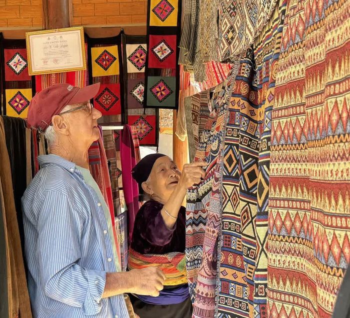Ông Roistacher Bob (82 tuổi), du khách Mỹ, chọn mua sản phẩm thổ cẩm tại thôn Lặn Ngoài, xã Pù Luông. Ảnh: Hoa Mai - TTXVN
