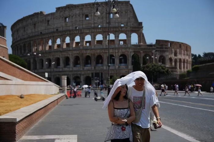 Du khách đi bộ dưới trời nắng nóng ở Italy ngày 1/8/2026. Ảnh: AP/Alessandra Tarantino.