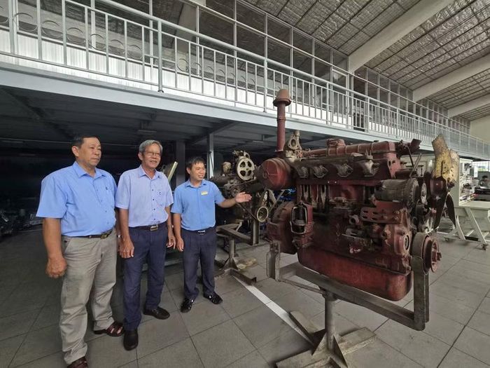 Thạc sĩ Lương Văn Vạn (bìa phải), Trưởng khoa Cơ khí Động lực giới thiệu về chiếc máy kéo được Nga tài trợ từ năm 1984, hiện vẫn dùng để sinh viên thực hành.