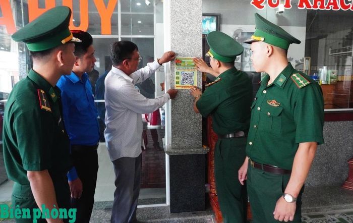 Cán bộ Đồn Biên phòng cửa khẩu Mỹ Quý Tây, Bộ đội Biên phòng tỉnh Tây Ninh phát tờ rơi, dán mã QR để người dân phản ánh các vụ việc liên quan đến an ninh, trật tự và hành vi vi phạm pháp luật ở khu vực biên giới. Ảnh: Đơn vị cung cấp