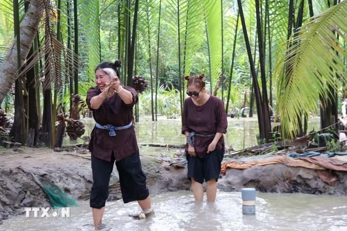 Du khách hào hứng với trò chơi bắt cá lóc tại Khu Du lịch Lan Vương (phường An Hội, tỉnh Vĩnh Long). (Ảnh: Thanh Hòa/TTXVN)