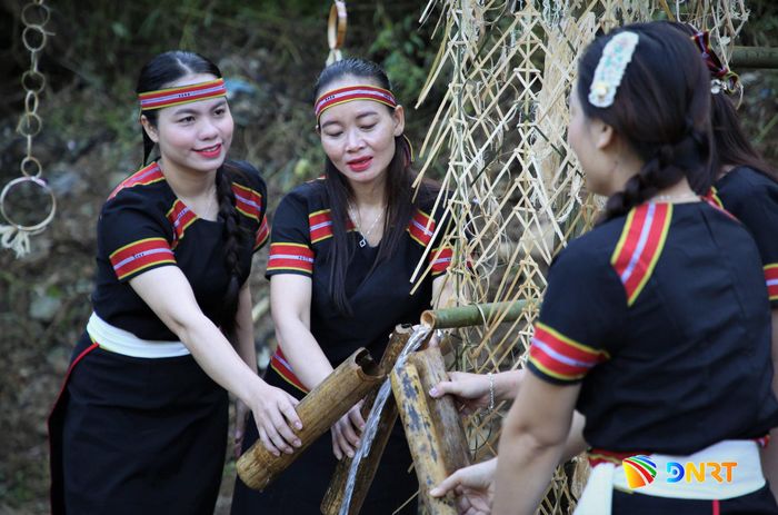 Phụ nữ M'Nông dùng ống lồ ô hứng nguồn nước từ thượng nguồn sau khi các già làng thực hiện xong nghi thức cúng thần nước. Ảnh: ALĂNG NGƯỚC
