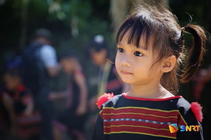 Một em bé diện sắc phục truyền thống, hồn nhiên theo câu chuyện của làng trong ngày cúng máng nước. Ảnh: ALĂNG NGƯỚC