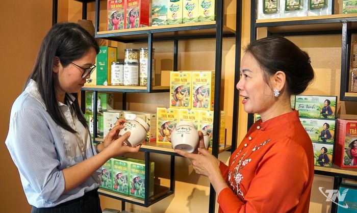 Chị Trần Thị Tuyết (bên phải) giới thiệu dòng trà đinh quà tặng cao cấp đóng bình gốm sứ Bát Tràng của HTX chè Tuyết Hương.