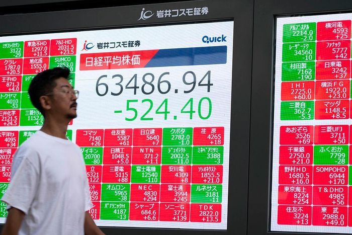 Người dân đi qua bảng điện tử hiển thị chỉ số Nikkei tại Tokyo, Nhật Bản. Ảnh: AFP/Yuichi Yamazaki