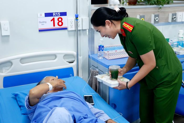 Thiếu tá Đào Thị Mai Hoa - Chủ tịch Hội Phụ nữ CAP Hoàng Mai ân cần hỏi thăm sức khỏe của một bệnh nhân khi tận tay trao suất cơm nghĩa tình