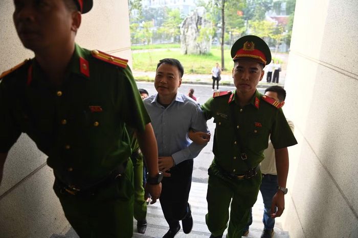 Khoảng gần 8h, bị cáo Nguyễn Hòa Bình được dẫn giải đến tòa trên một xe chở phạm riêng. Dáng vẻ bề ngoài của ông Bình không khác nhiều so với thời điểm bị khởi tố. Ông Bình bước xuống xe với vẻ khá bình thản, có lúc còn cười rất tươi. Ông bị cáo buộc rửa tiền giúp Mr Pips hơn 319 tỷ đồng.