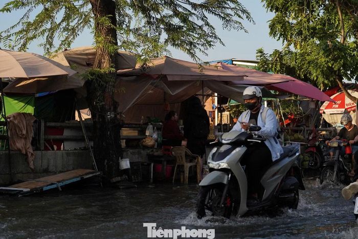 Nước tràn vào khu vực trước các gian hàng, ảnh hưởng đến hoạt động kinh doanh của người dân ven đường.