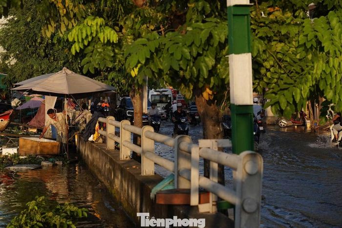 Mực nước kênh Tẻ dâng cao tràn lên mặt đường Trần Xuân Soạn.